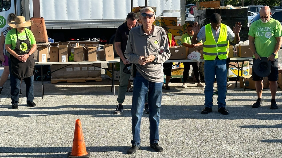 A pastor leads volunteers in prayer before the Place of Hope food distribution line opens.