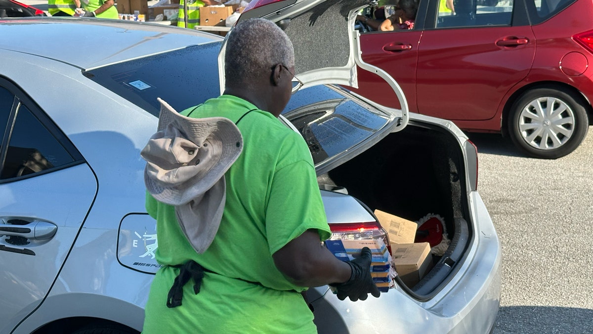 A volunteer loads cheese into the boot of a car at the Place of Hope food distribution line.