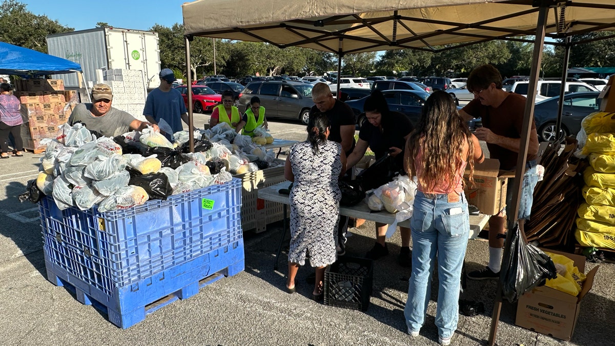 Voluntarios clasifican bolsas de comida antes de la distribución de alimentos en el autoservicio de Place of Hope.