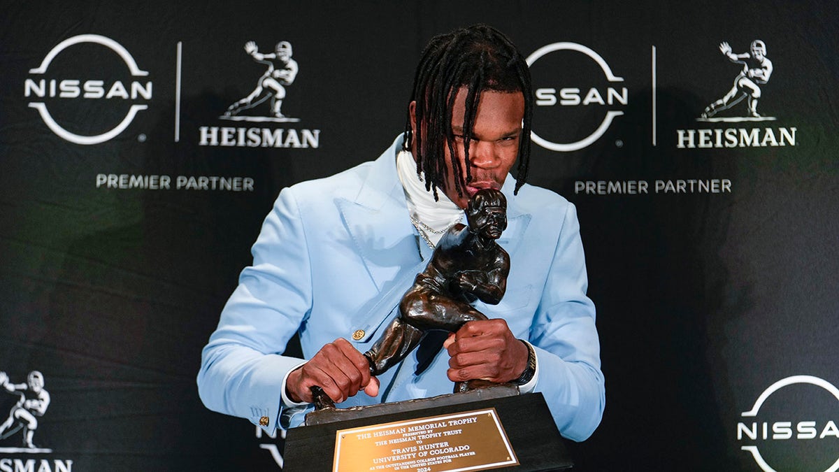 Travis Hunter kisses the Heisman Trophy