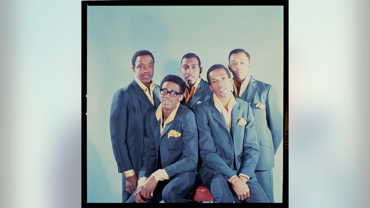 The Temptations in matching blue and yellow suits posing together