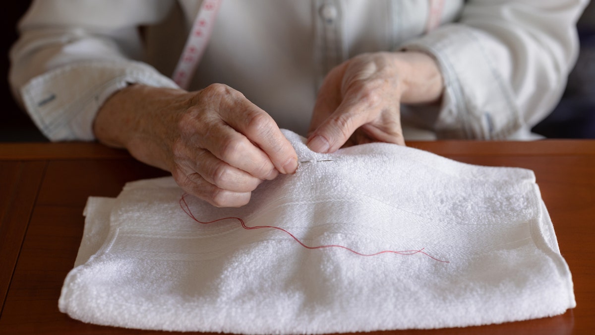 Woman sewing a bath towel