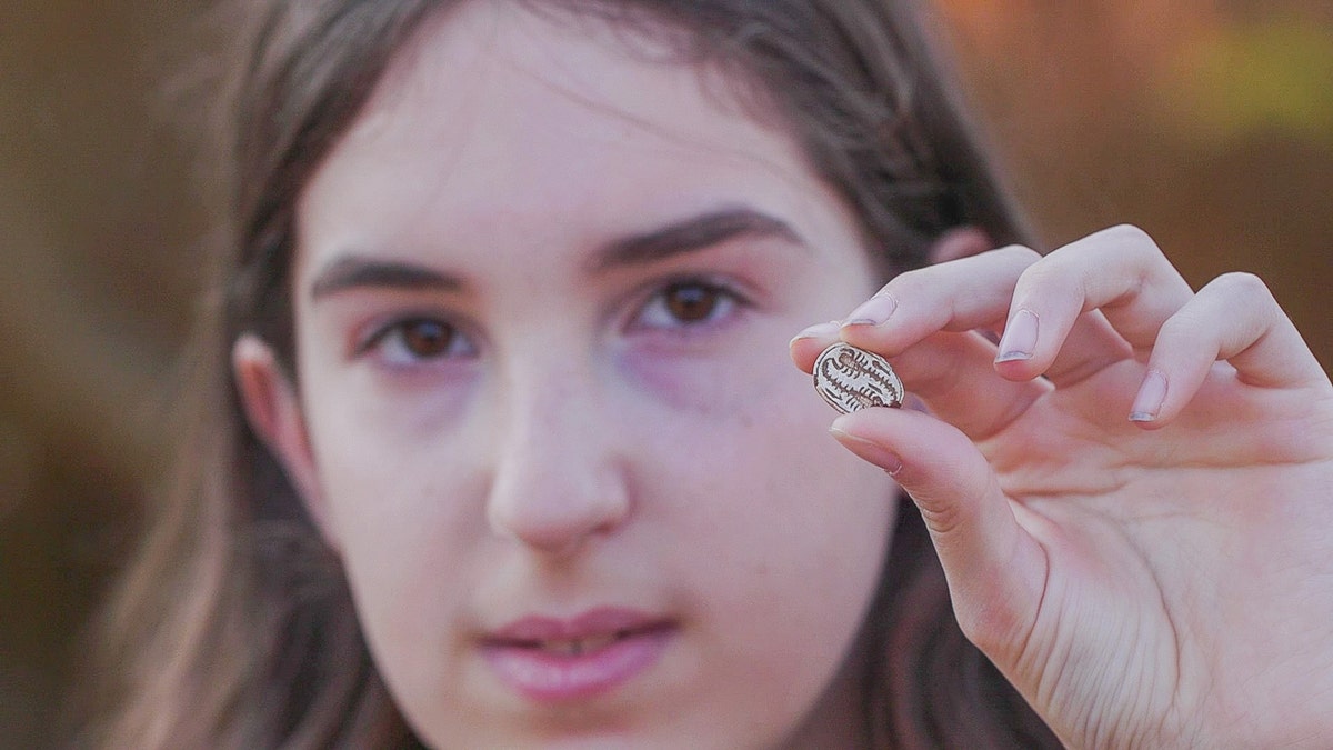 12-year-old Dafna Filshteiner holding an ancient Egyptian amulet that she discovered