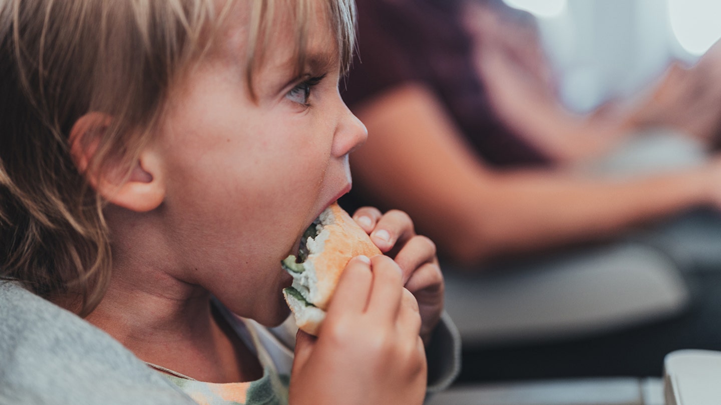 little boy eating burger on flight