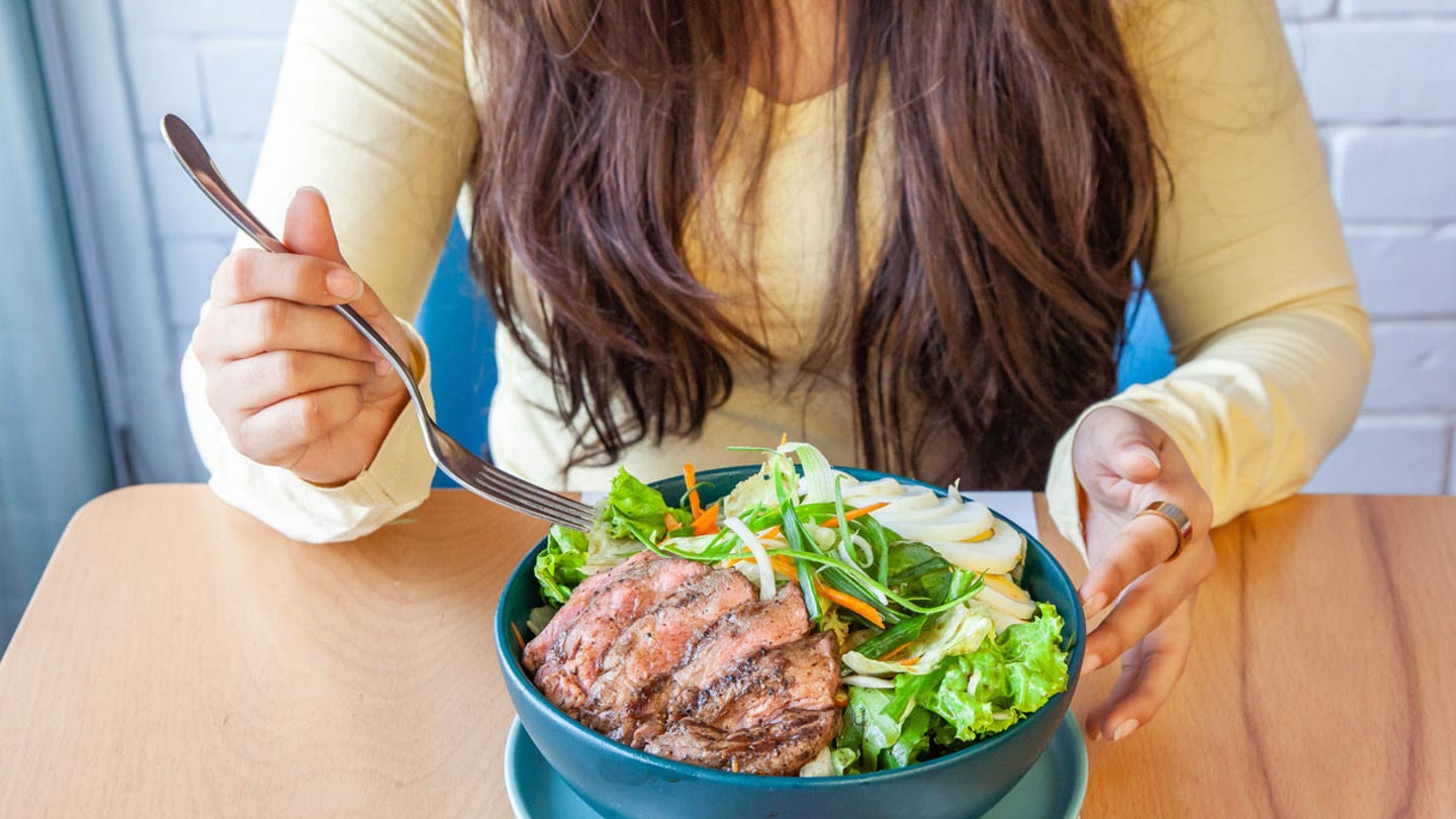 woman eating steak salad