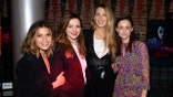 America Ferrera in a black jacket holds onto Amber Tamblyns arm, wearing a red suit jacket and white lace top stands next to Blake Lively in a black sweater top over a white shirt next to Alexis Bledel in a printed dress