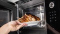 A hand removes a plate of rotisserie chicken from the microwave. - Fox News