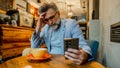 Mature man trying to contemplate bad news he is reading online on his smartphone while sitting in a caf&eacute; - Fox News
