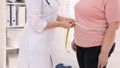 Nutritionist measuring overweight woman's waist with tape in clinic, closeup - Fox News