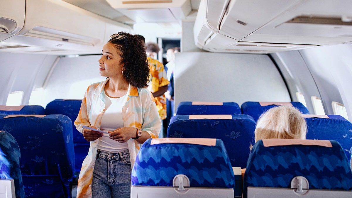 A woman looking for a seat on a plane