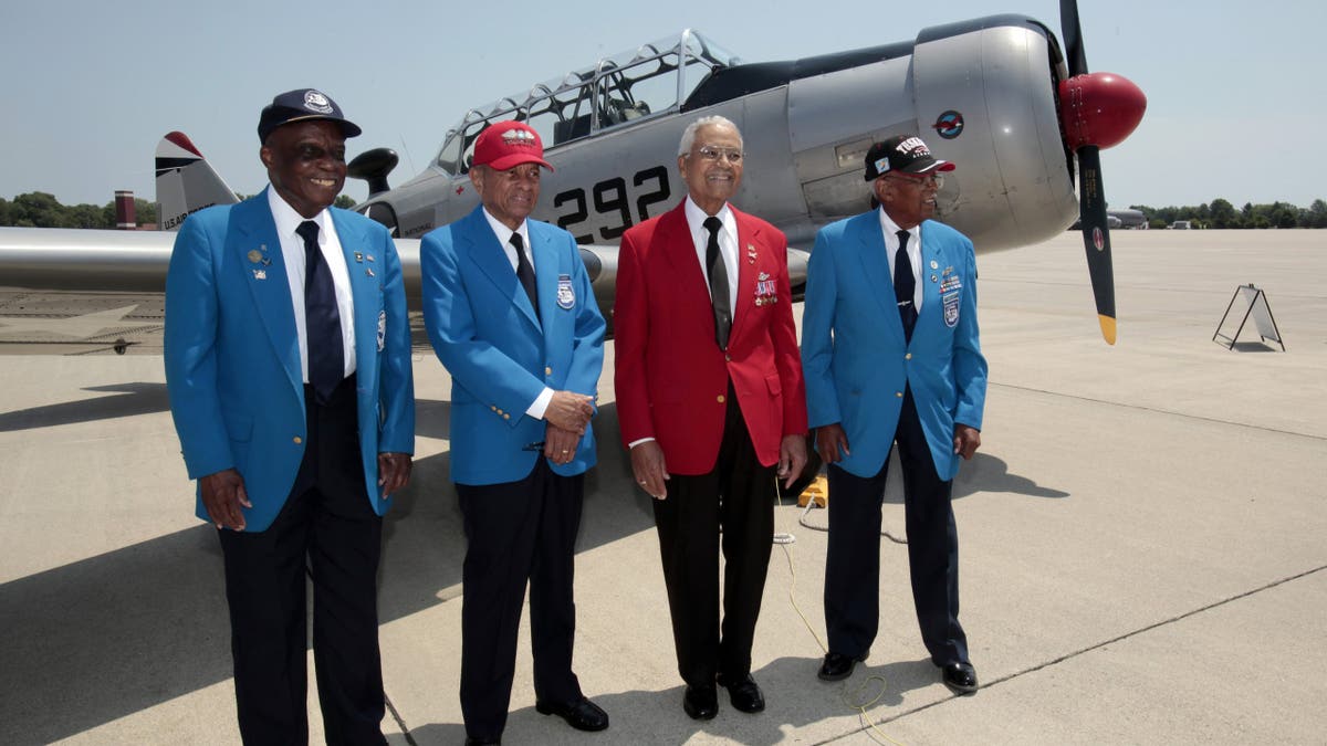 Tuskegee Airmen on tarmac by vintage plane