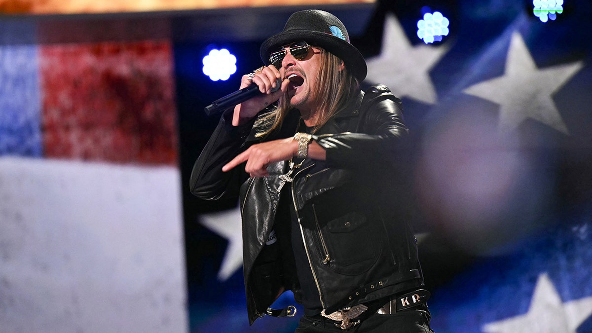 Kid Rock wears a black leather jacket and hat and sings enthusiastically on stage at the RNC