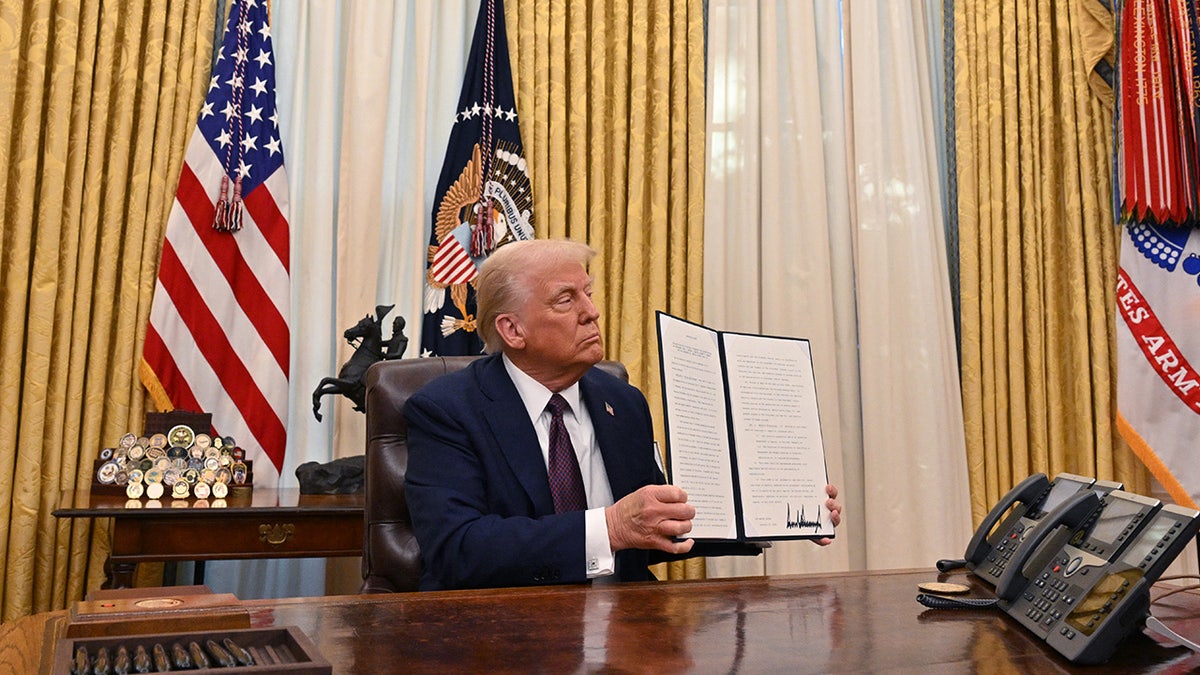 President Donald Trump holds document