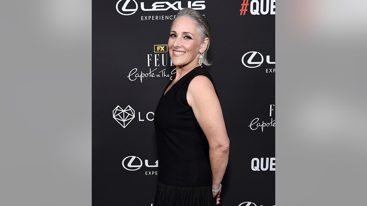 Ricki Lake with a black dress turns sideways and smiles for a picture