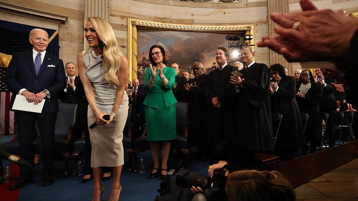 Carrie Underwood leans over and smiles after performing "America The Beautiful"