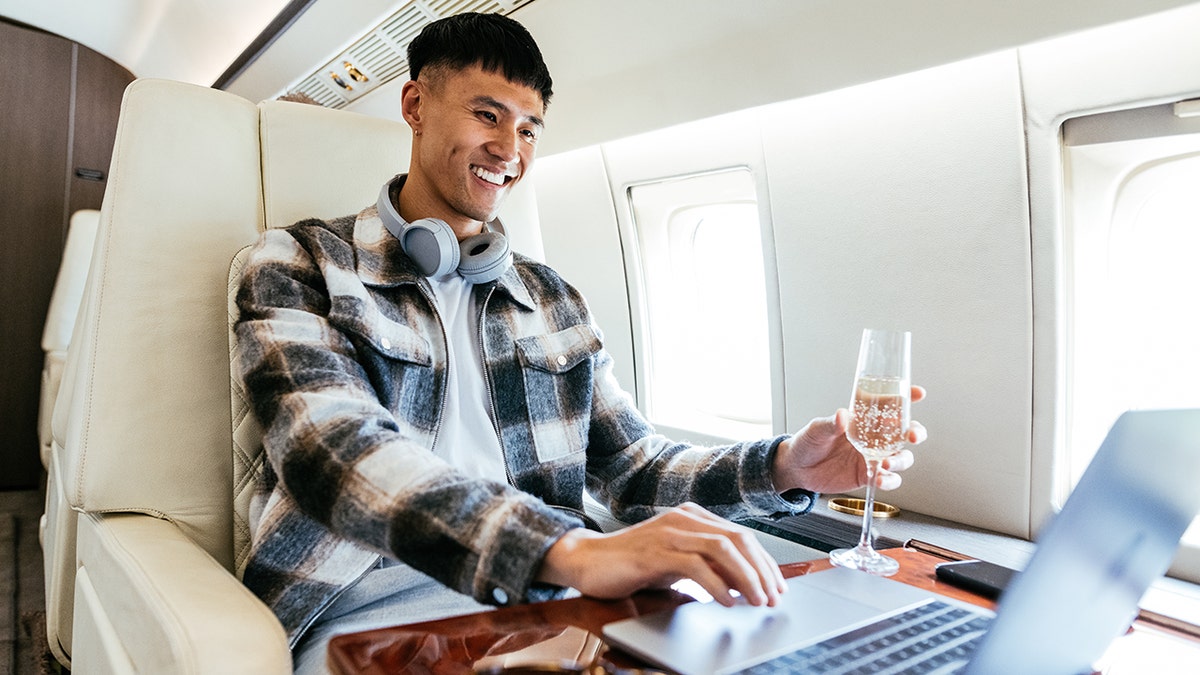 A man drinks champagne on the plane