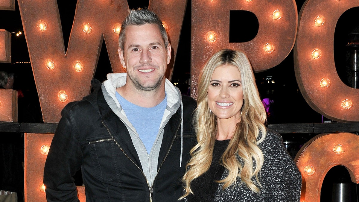 Ant Anstead in a blue shirt and black sweatshirt smiles next to wife Christina in a black and white sweater