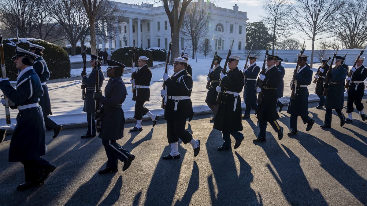 A joint US military honor guard was photographed outside the snow-covered White House 