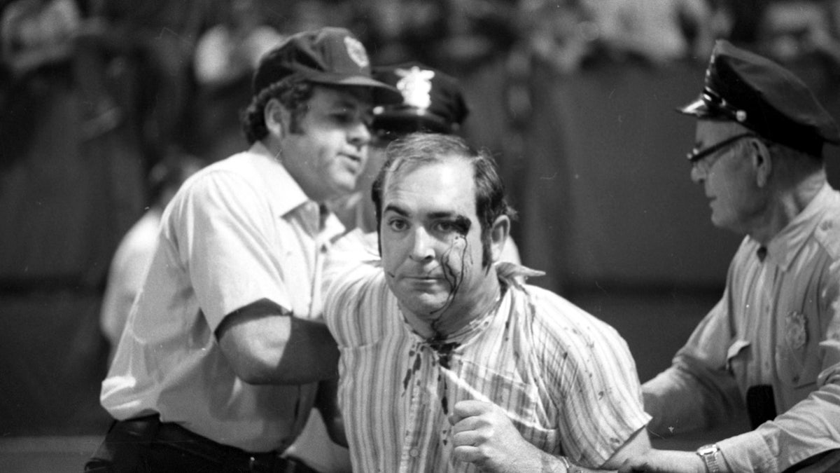 A drunken fan is helped off the field after suffering a minor injury during a game between the Texas Rangers and Cleveland Indians on June 4, 1974, at Cleveland Municipal Stadium.