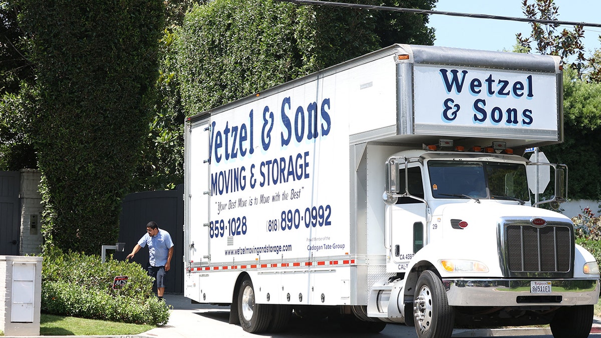 A large white truck that says Wetzel & Sons in blue lettering leaves the driveway of Ben Affleck's home