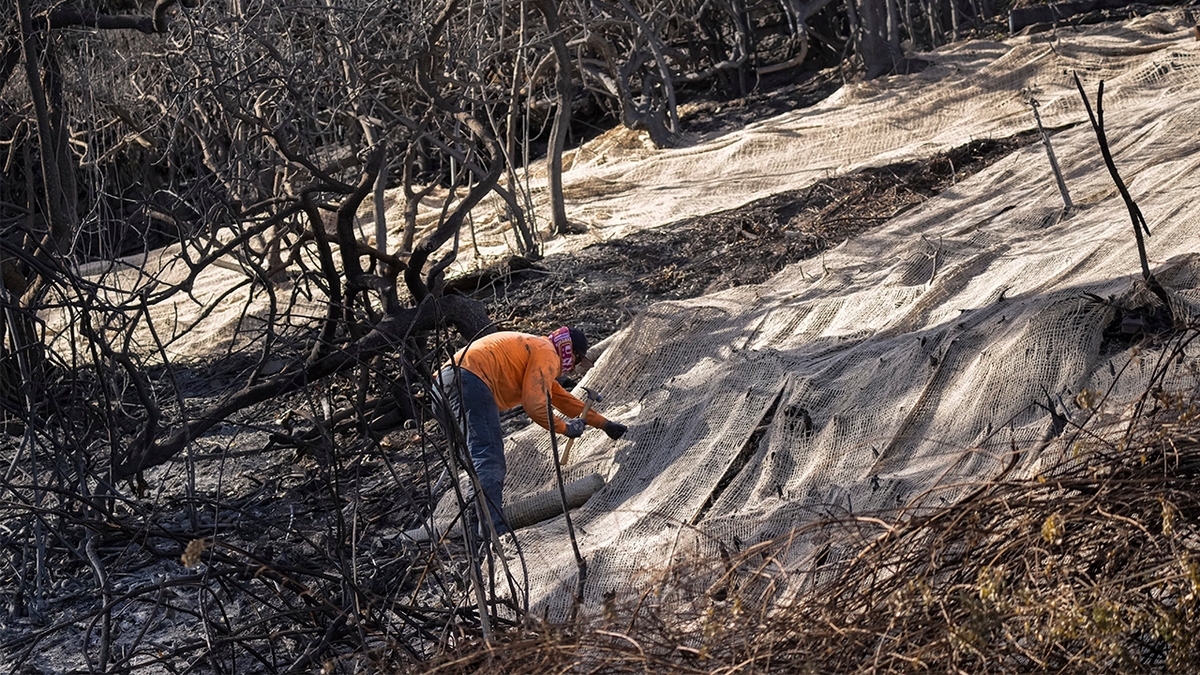 Workers secure a net to prevent mudslides