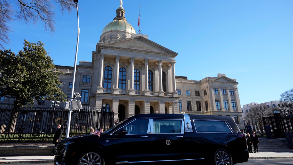 The hearse carrying the flag-draped casket of former President Jimmy Carter pauses outside the State Capitol in Atlanta, Saturday.