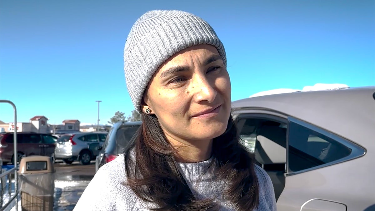 Woman stands in parking lot by car