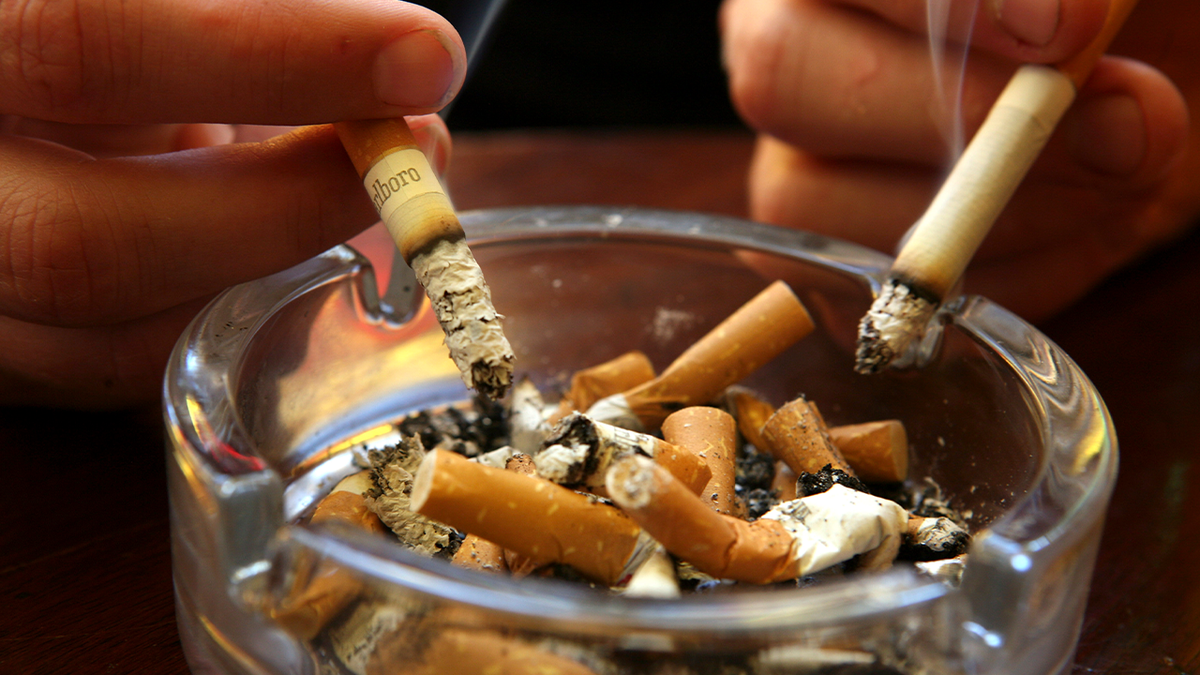 A couple wipes cigarette butts in an ashtray