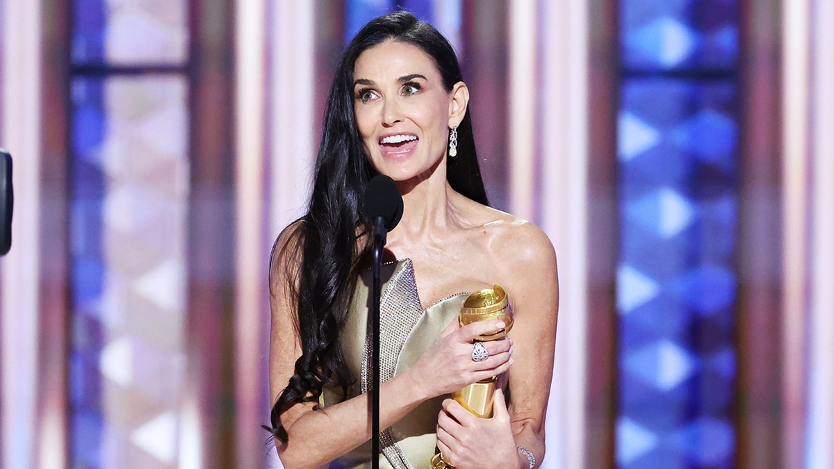 Aktris Demi Moore tersenyum di atas panggung dengan penghargaan Golden Globe