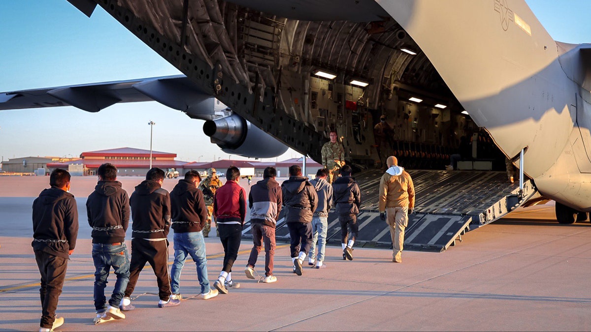 Os migrantes se movem em direção ao avião para exílio