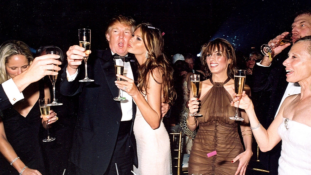 Donald Trump and his girlfriend, model Melania Knauss (later Trump), raise their glasses for a New Year's toast 