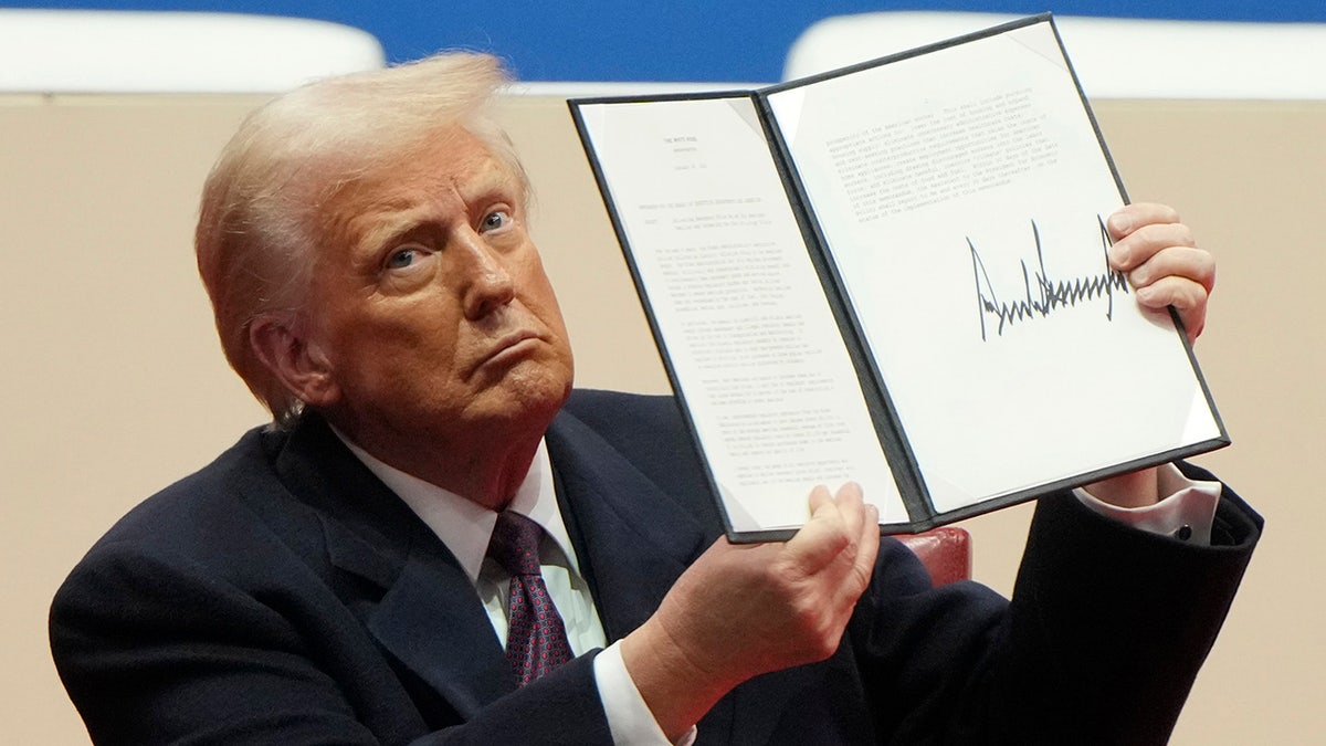 President Donald Trump holds an executive order after signing