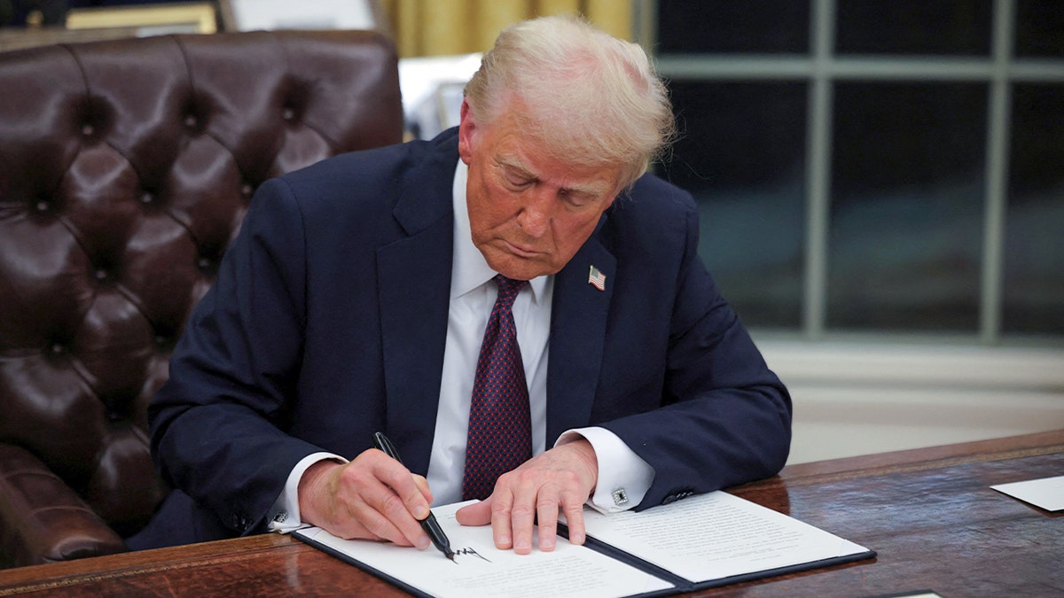 President Donald Trump signs documents at the Oval Office