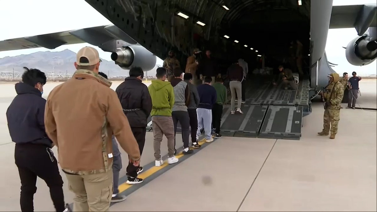 row of people walking into military plane