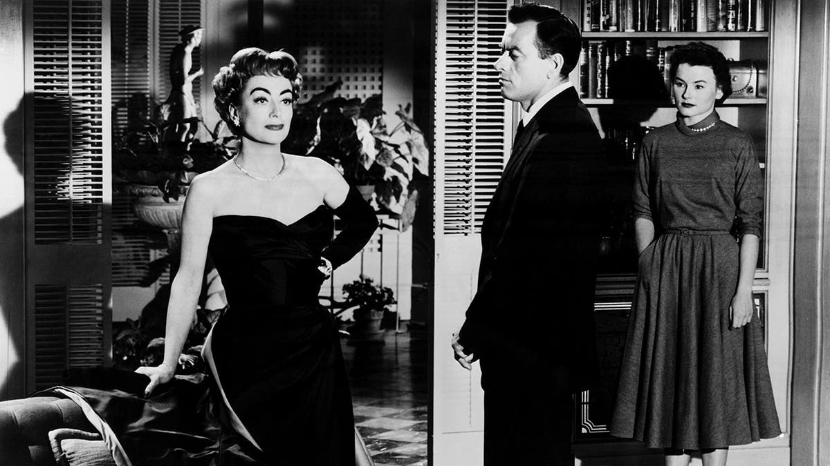 Joan Crawford in a strapless glamorous black costume acting out a scene from Queen Bee.