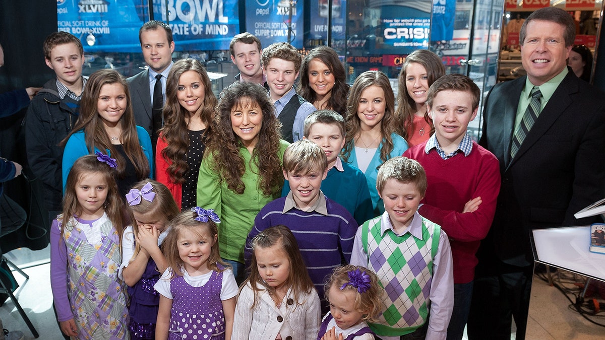 The Duggar family gathered together and smiling.