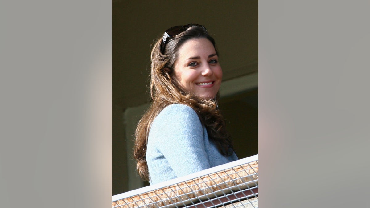 Kate Middleton smiling wearing a light blue sweater.