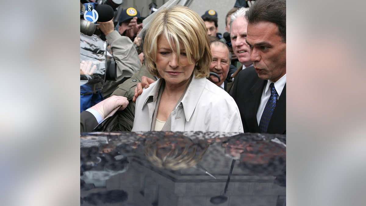 Martha Stewart in a white blouse and blazer stepping inside a car.