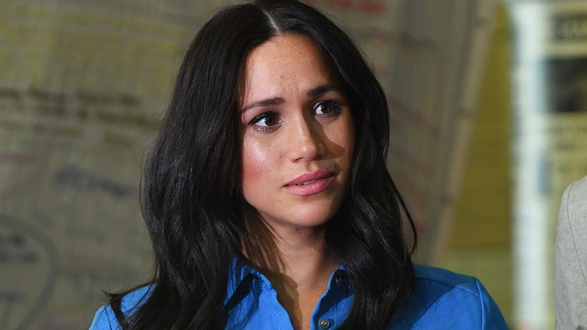 A close-up of Meghan Markle wearing a bright blue shirt.