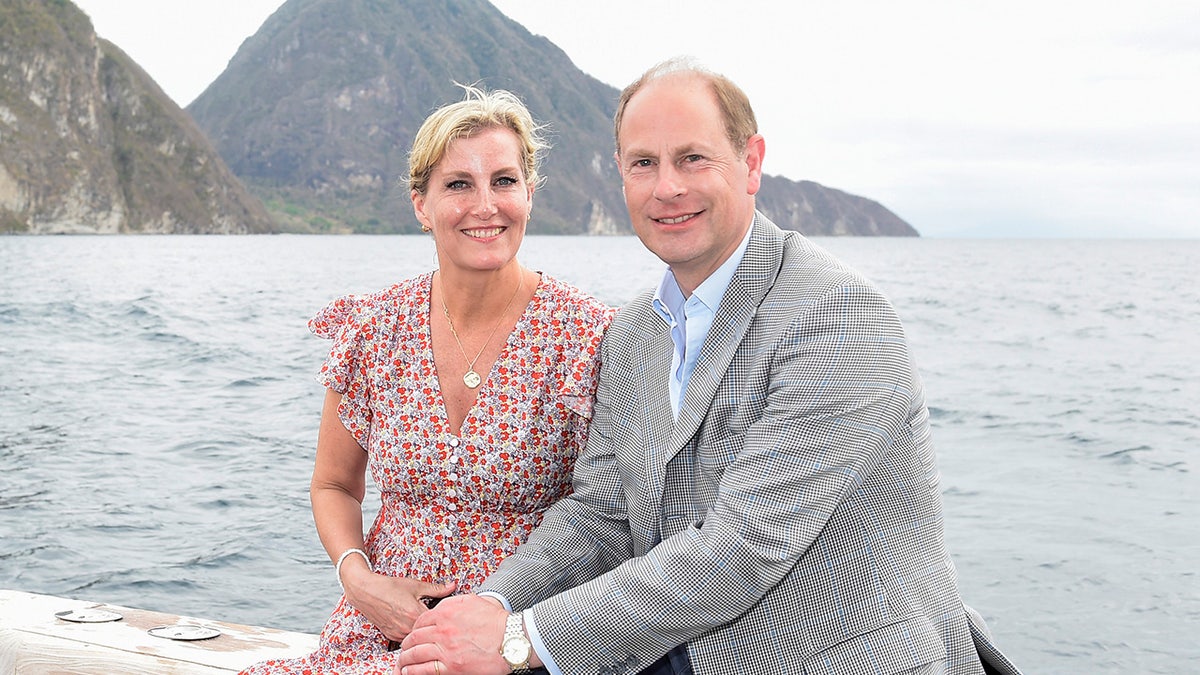 Sophia, Duchess of Edinburgh on a boat wearing a multiprinted dress sitting next to Prince Edward in a grey blazer and light blue shirt.