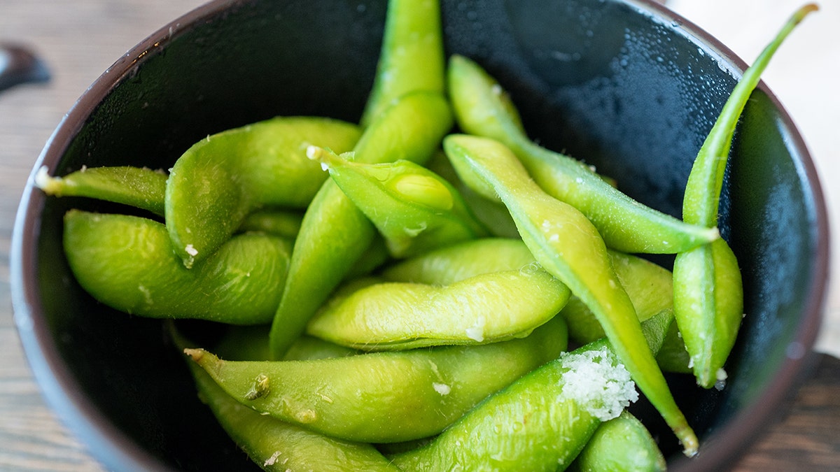 A close -up of a bowl of cooked edamame soybeans.