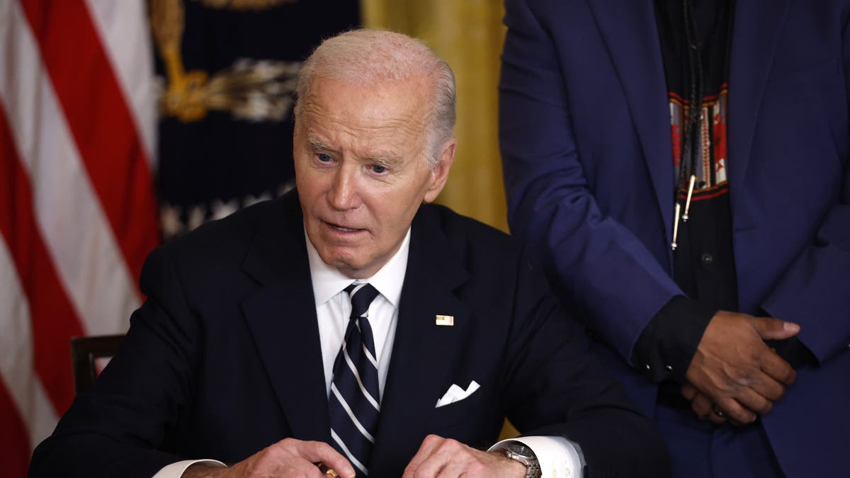 El presidente Joe Biden firma documentos en su escritorio