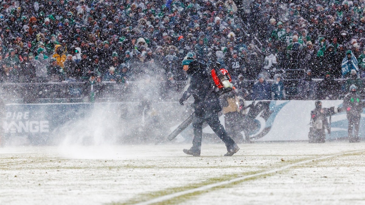 Los encargados del campo corren hacia el campo durante el juego con quitanieves para despejar las líneas en condiciones de tormenta de nieve durante el desempate divisional de la NFC entre los Eagles y los Rams en el Lincoln Financial Field el 19 de enero de 2025 en Filadelfia, Pensilvania.