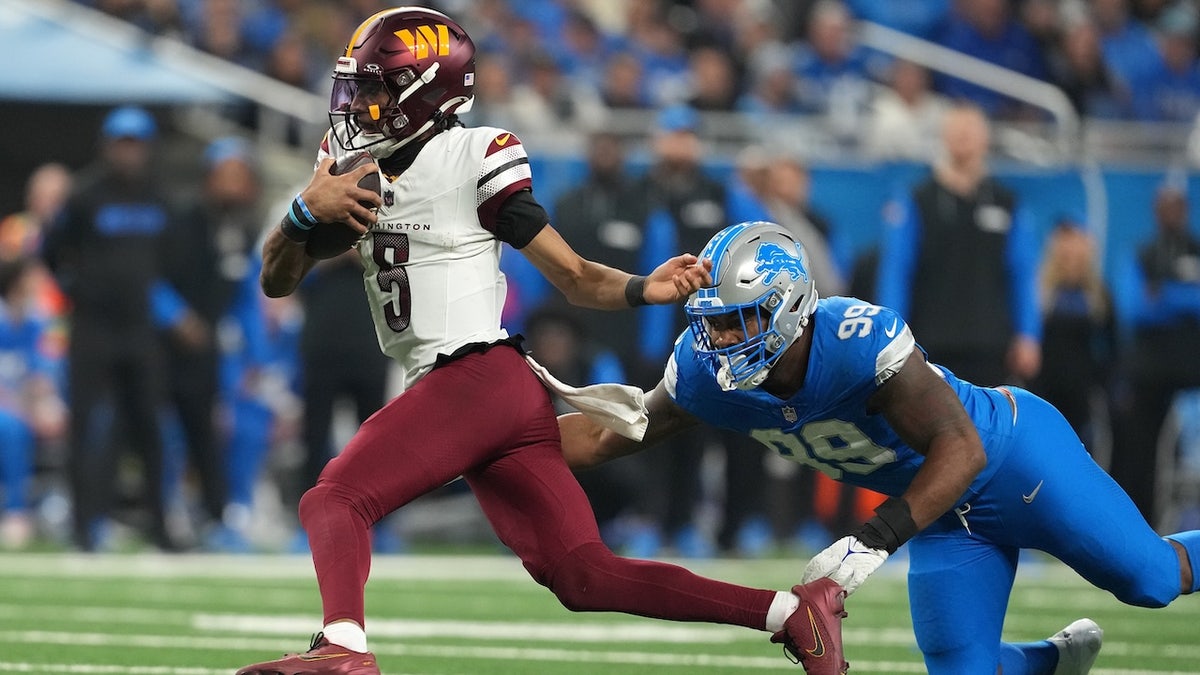 Jayden Daniels #5 of the Washington Commanders runs the ball against Za'Darius Smith #99 of the Detroit Lions during the fourth quarter in the NFC Divisional Playoff at Ford Field on January 18, 2025 in Detroit, Michigan. 