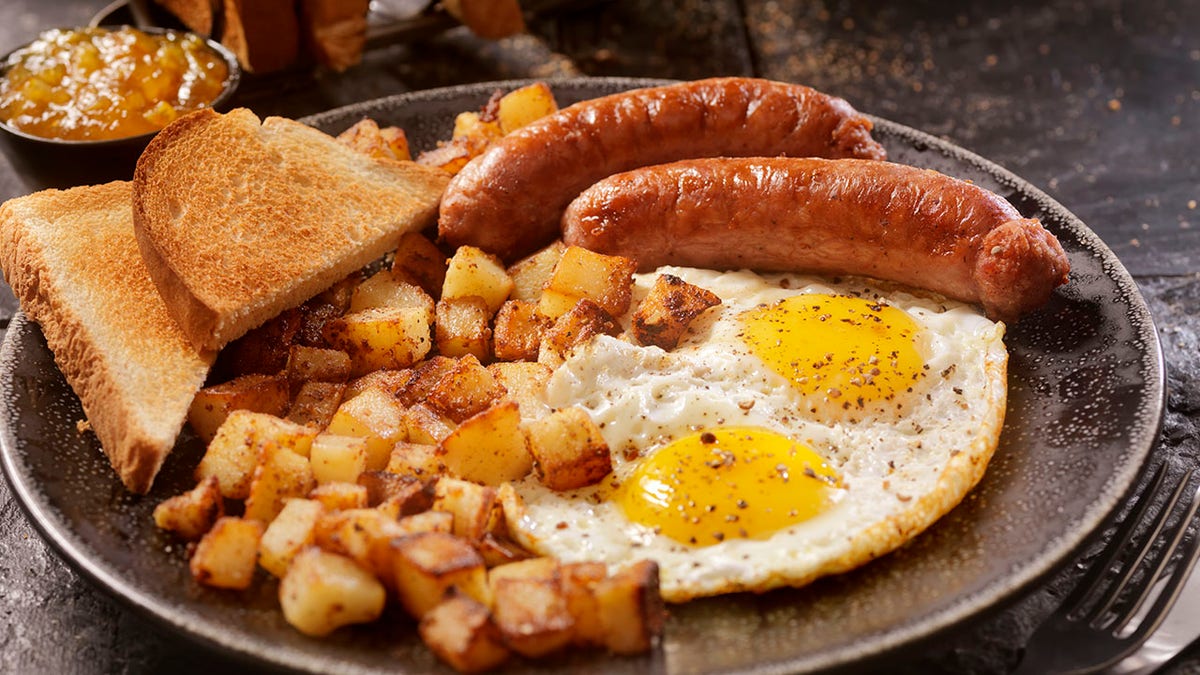 Breakfast with sunny side up eggs, sausage, hash browns and toast