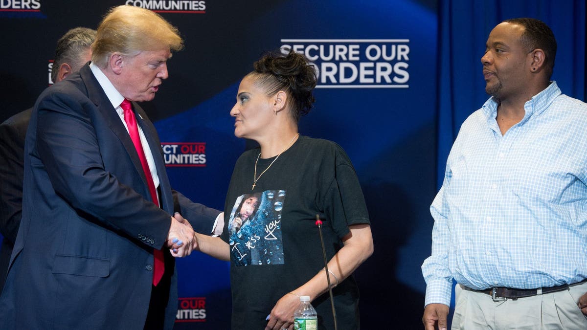 US President Donald Trump shakes hands with Elizabeth Alvarado, alongside Robert Mickens,