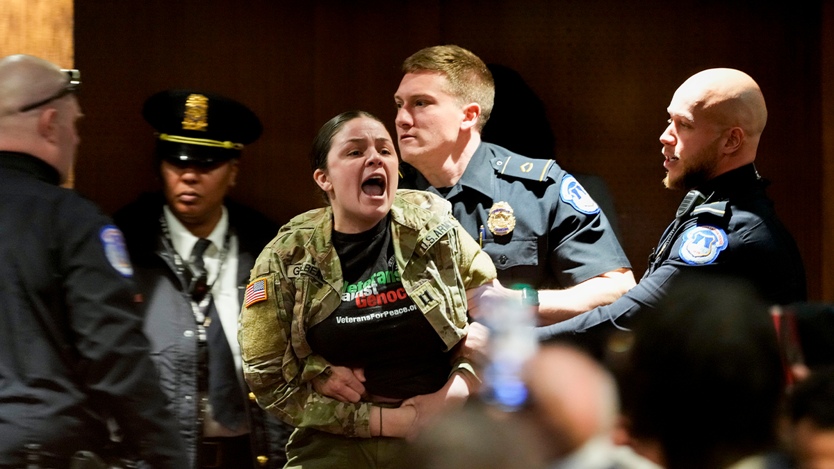 Hegseth protester with pro-Palestinian T-shirt under fatigues