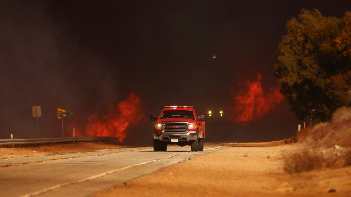 A fire truck drives past flames caused by the Hughes Fire in Castaic, Calif., Wednesday. 