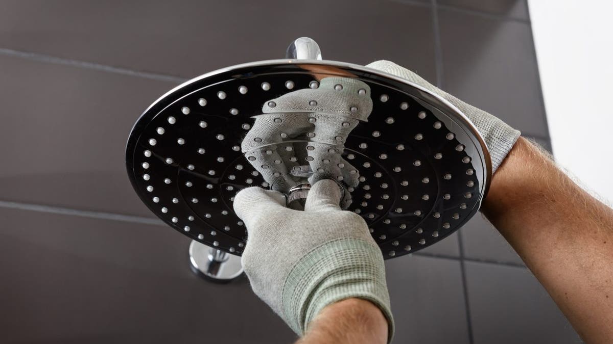 Worker's hands install the head of the built-in shower faucet.