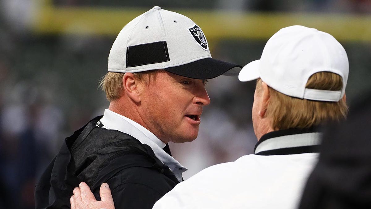 Jon Gruden talks to Mark Davis on the sidelines